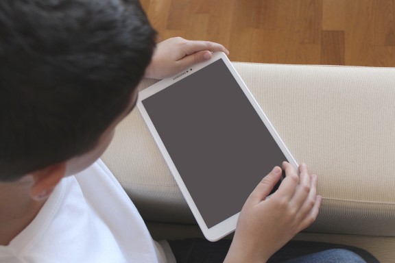 A child engrossed in a mobile device, illustrating the screen habits carried into young seafarers’ free time
