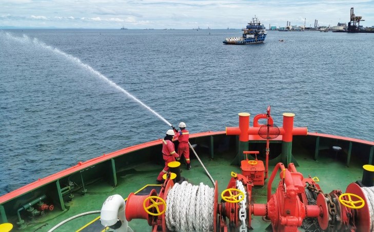 Fire party responding to an engine room fire drill on board a merchant vessel